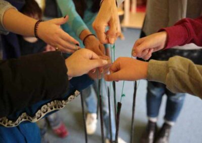 Viele Hände die Stäbe an Fäden in einem Kreis halten