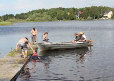See mit Steg und Boot sowie jungen Menschen